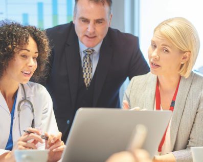 healthcare professionals talking and looking at a laptop