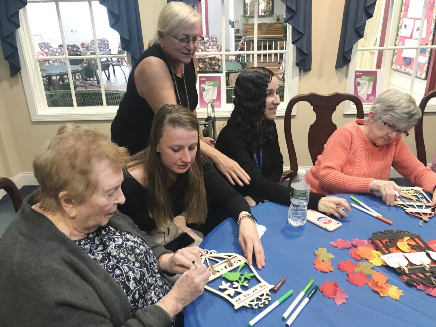 Professor Madori and students at table working on crafts with participants at assisted living facility
