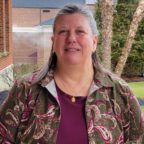 Ann smiling outside wearing eggplant colored shirt with green paisley sweater