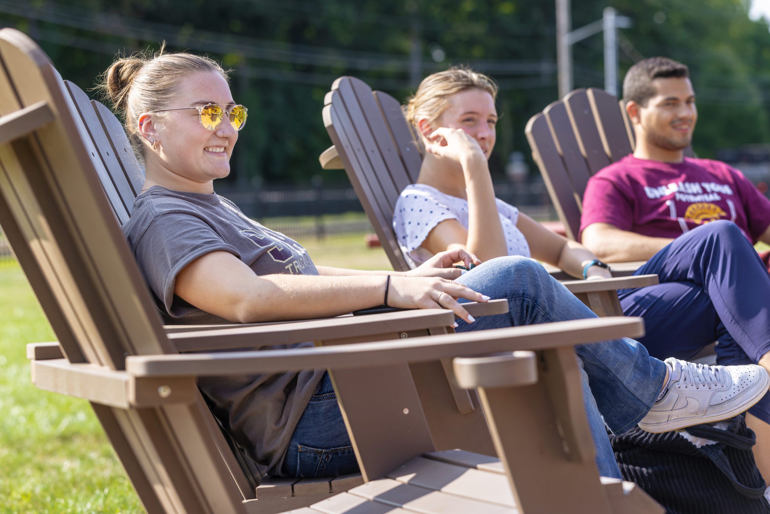 Two female and one male student sitting in wooden chairs.