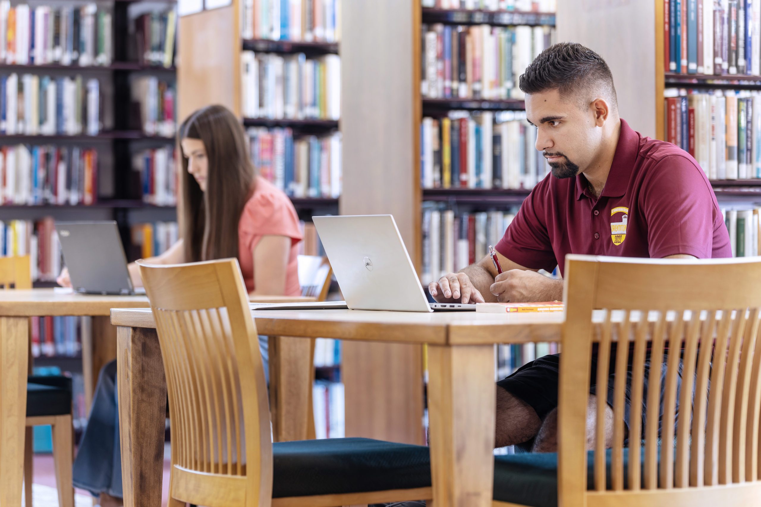 Two students, male and female, studying in the library.