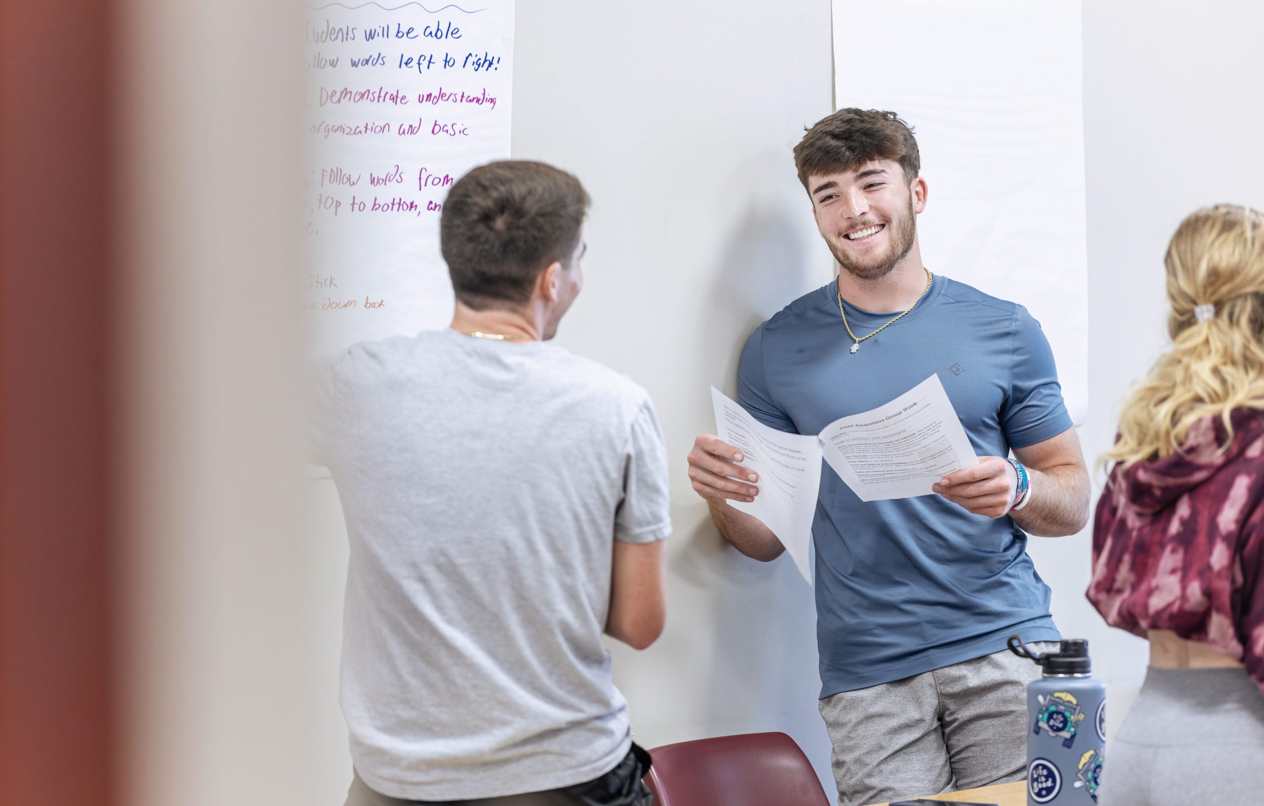 Two male students talking in the classroom.