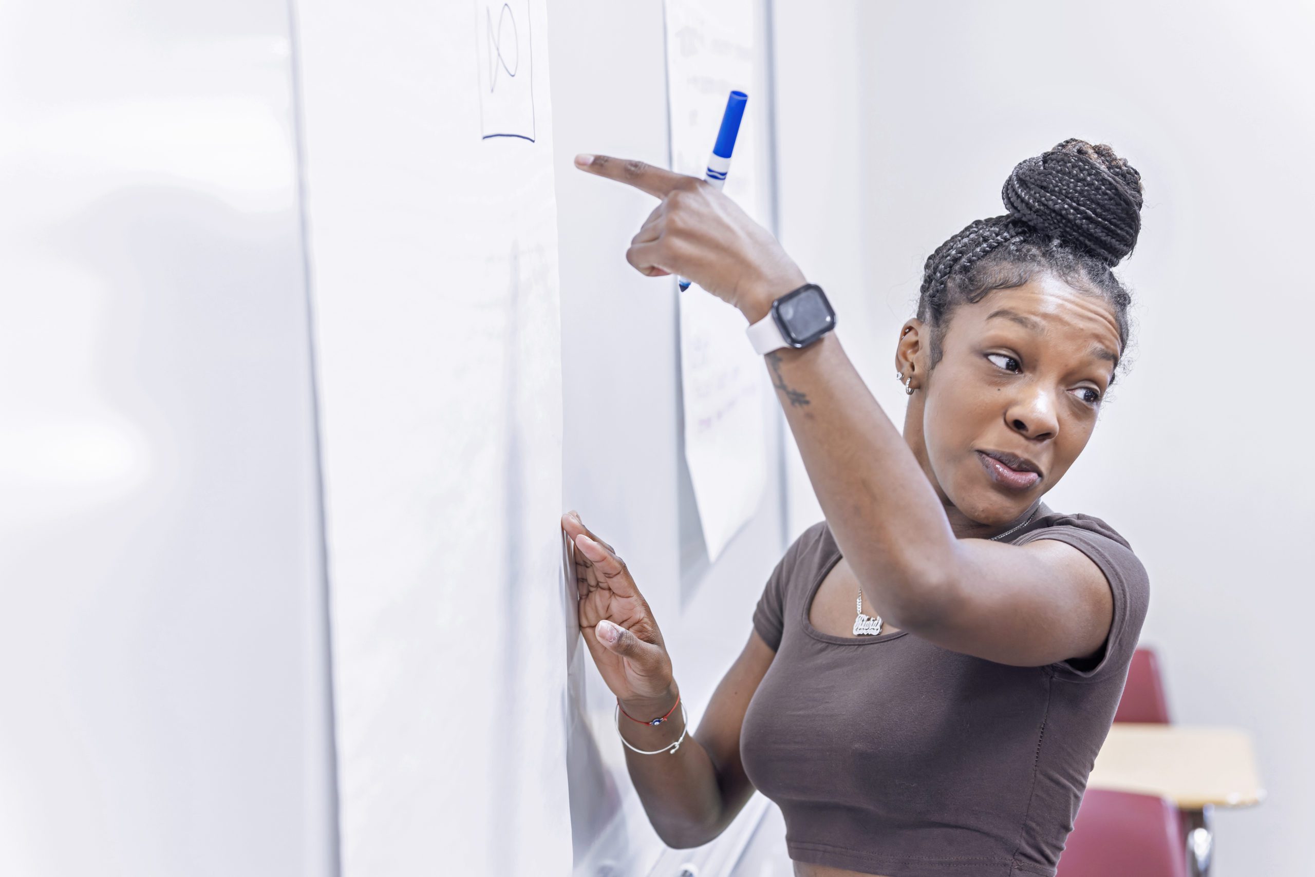 A female student writing on a paper on the wall.