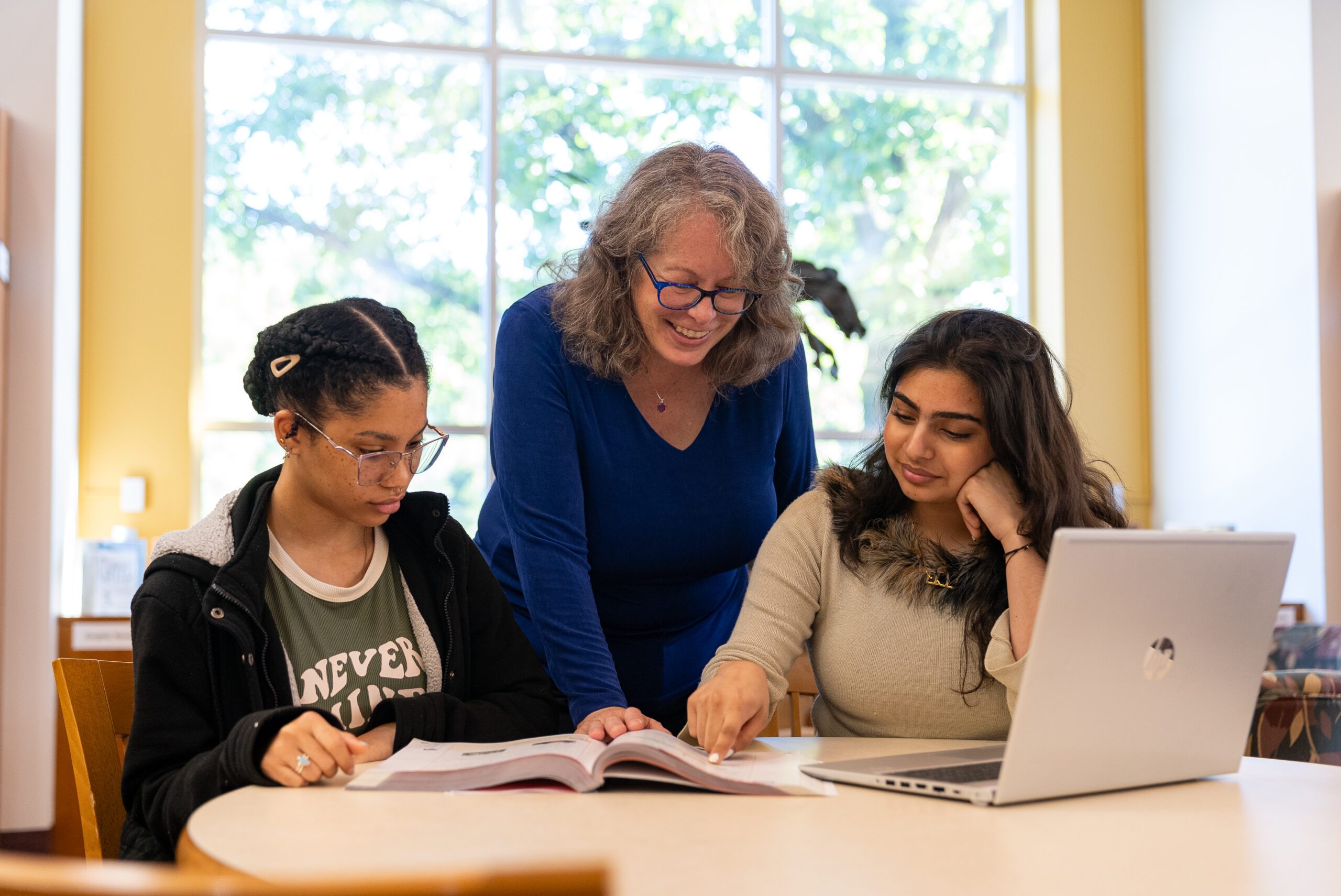 Dr. Roglieri in library with two students looking at laptop screen