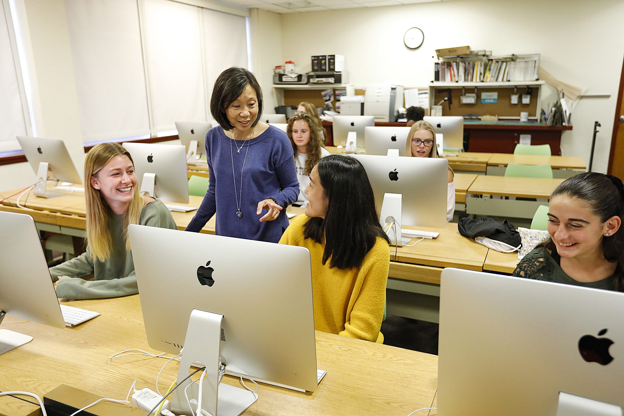 Students at computers talking with professor