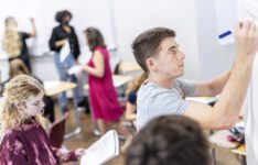 Students in a classroom writing on white boards.