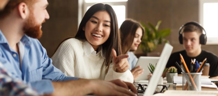 A group of students sitting at desks and using their laptops