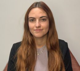 Lucille smiling wearing silver necklace, black blazer, and gray shirt
