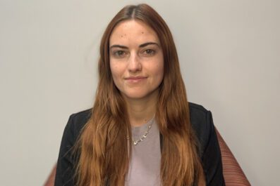 Lucille smiling wearing silver necklace, black blazer, and gray shirt