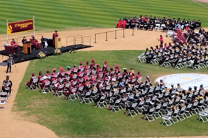 Commencement 2023 image from seats at Clover stadium while graduates are on the field in regalia walking across stage