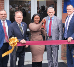 President Daly, VP Mike DiBartolomeo, Ed Day, Sonya Smith, and Louis Scamardella smiling and getting ready to cut maroon ribbon in front of new SBDC sign