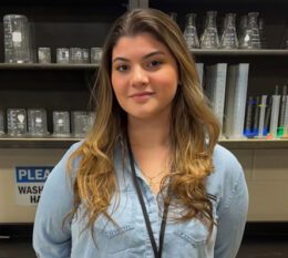 Madison smiling with lab materials in background in cabinet