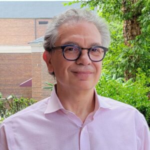 Alfredo smiling wearing glasses and pink dress shirt