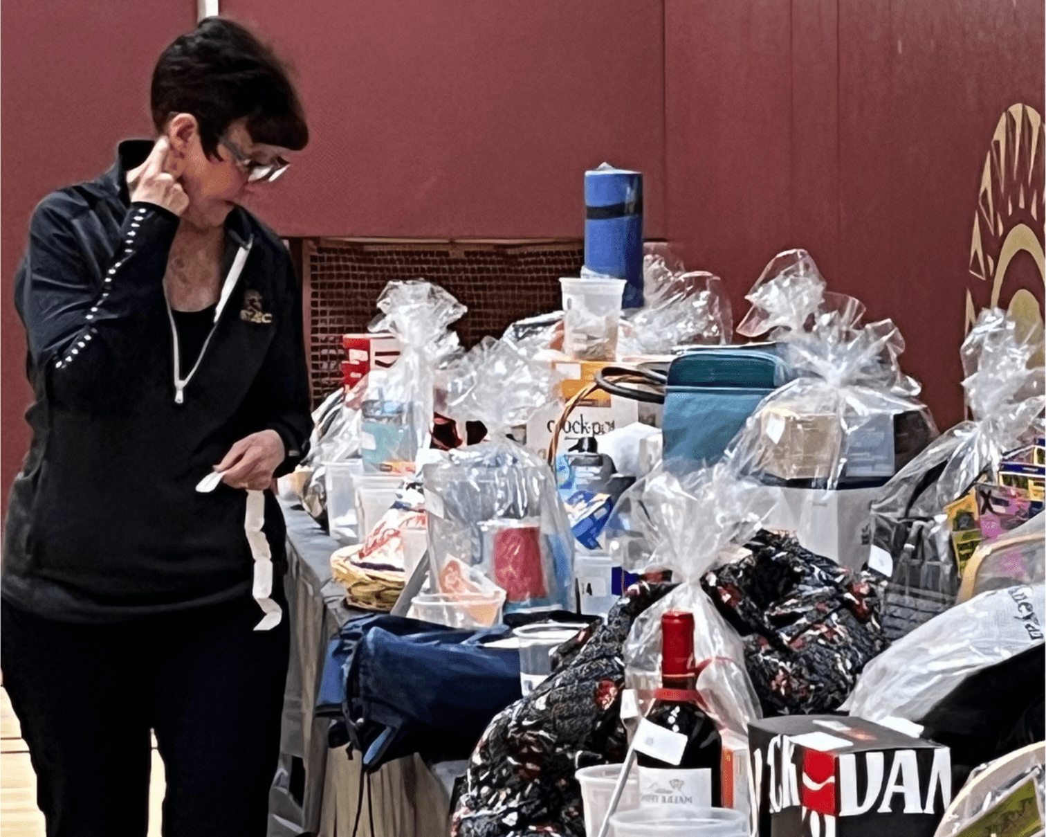 Woman standing next to a table looking at items being offered in a silent auction.