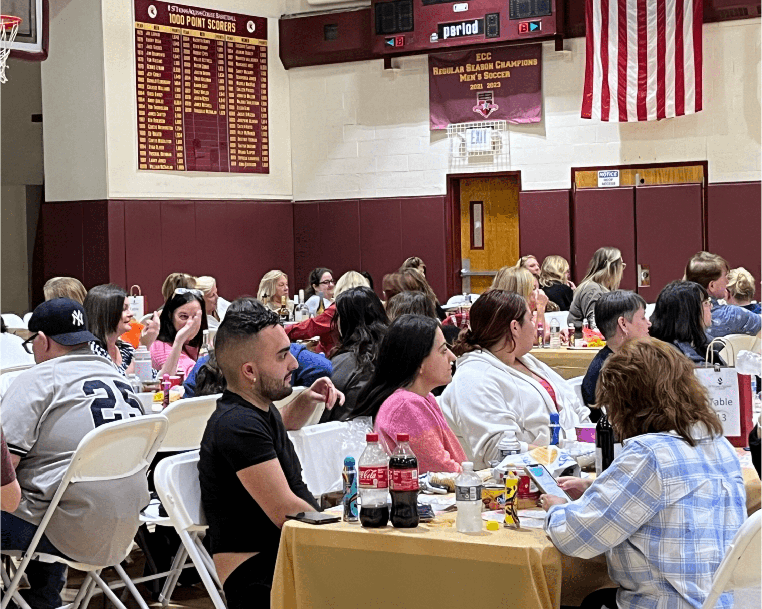 People seated at tables in the Aquinas Gym.