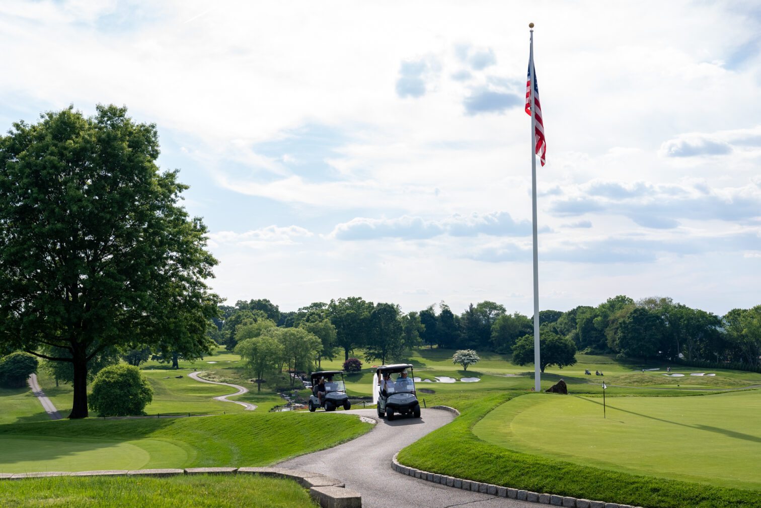 Golf course with a cart on the path and U.S. flag