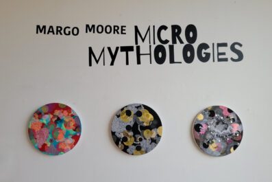 Margo Moore Micro-Mythologies text with three colorful circular designs on wall