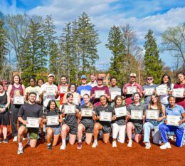 Group of 4.0 student athletes and administration on field smiling for group photo