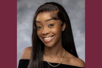 Laila smiling for high school yearbook photo wearing black dress and necklace smiling